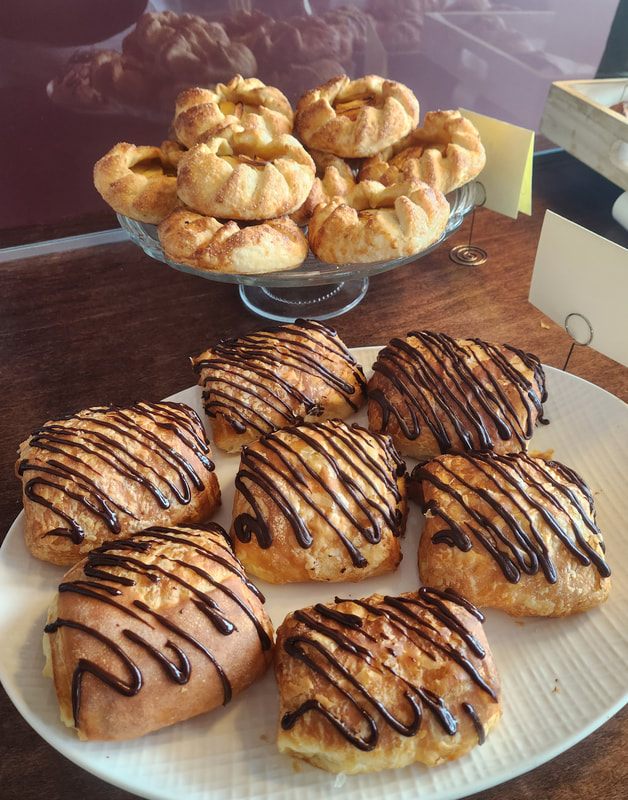 Apple galettes on a glass stand beside chocolate danishes