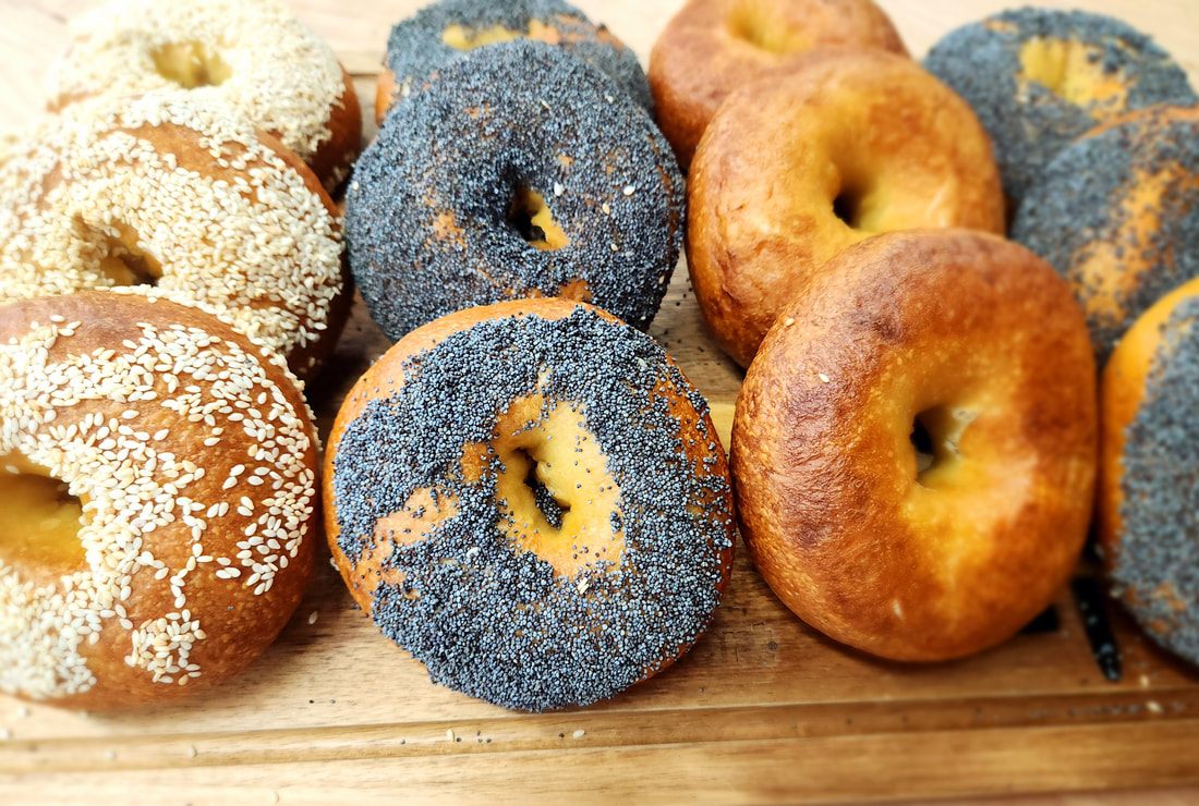 Sesame, poppy seed and plain bagels arranged on a wooden board
