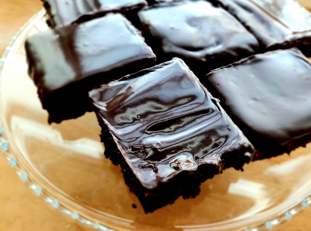 Thick chocolate brownies under a glossy chocolate glaze