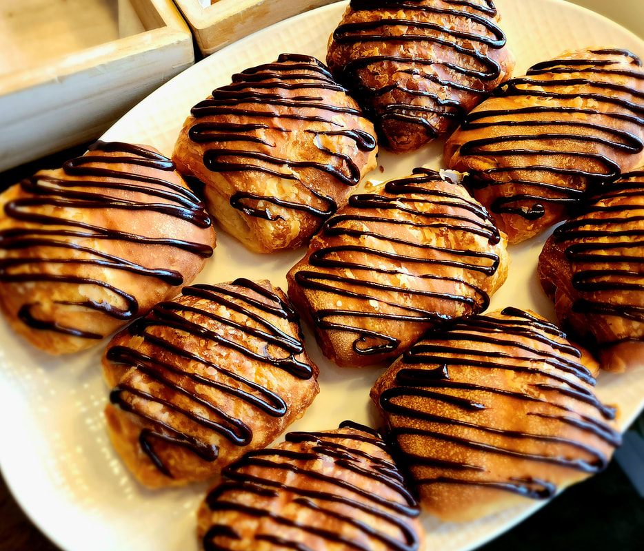 Chocolate-drizzled danishes arranged on a cream platter